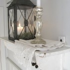 White shelf with lantern and mercury glass candle.