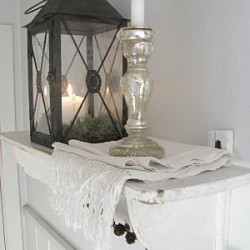 White shelf with lantern and mercury glass candle.
