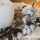 Christmas decoration in white, silver and browns with pine cones and disco ball