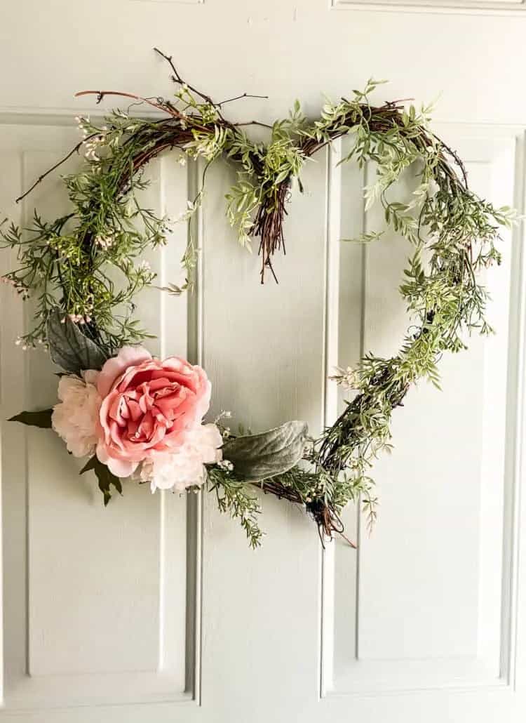 grapevine wreath in heart shape decoratd with greenery and flowers