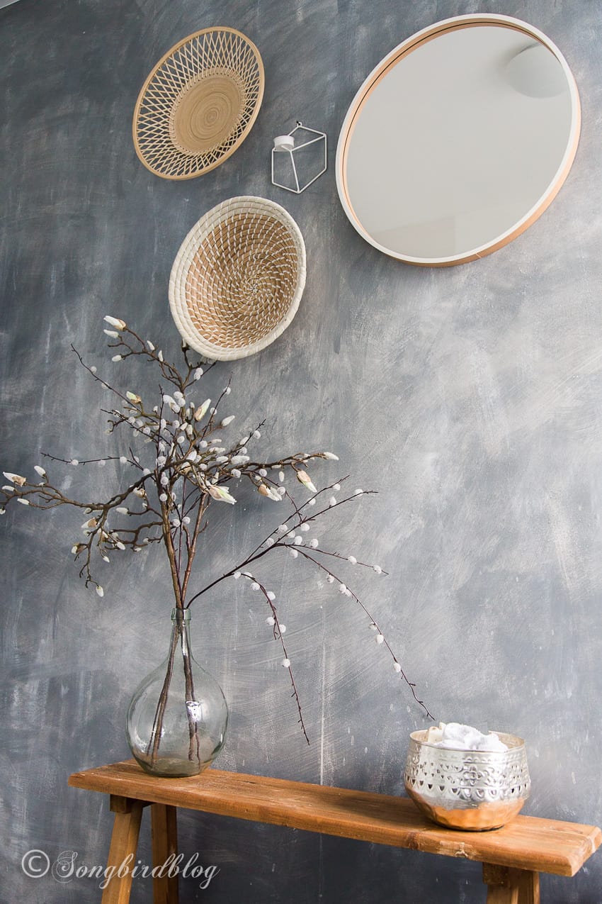 grey painted faux concrete wall with round baskets and mirror