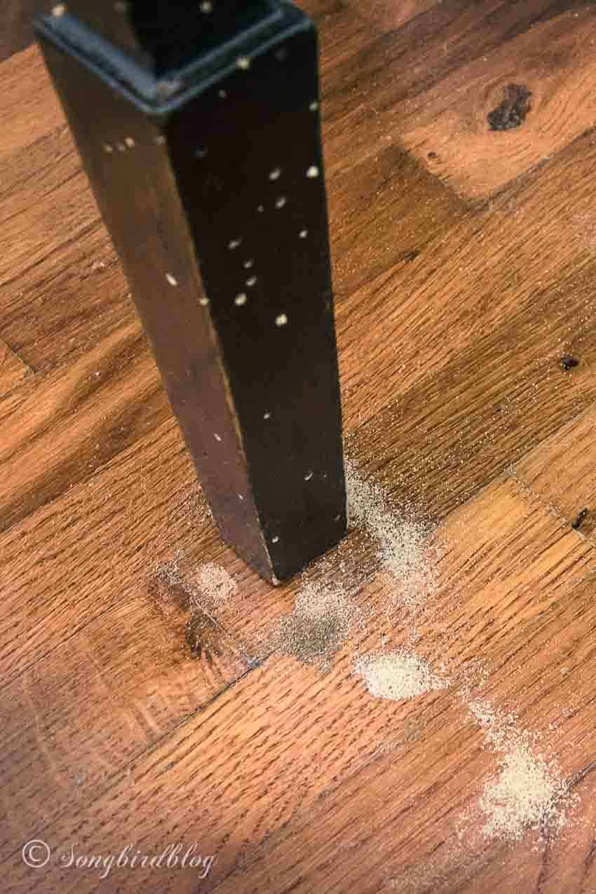 Table leg with tiny holes and fresh sawdust on floor