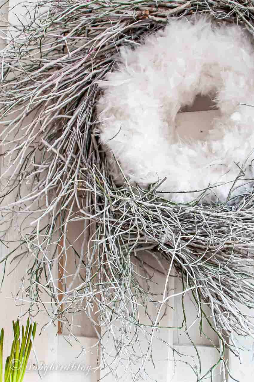 white painted twig wreath with a feather wreath in the center