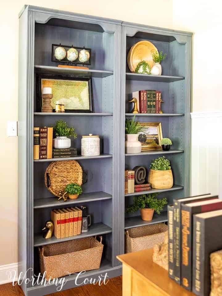 blue painted bookcase filled with vintage books and accessories in a traditional style
