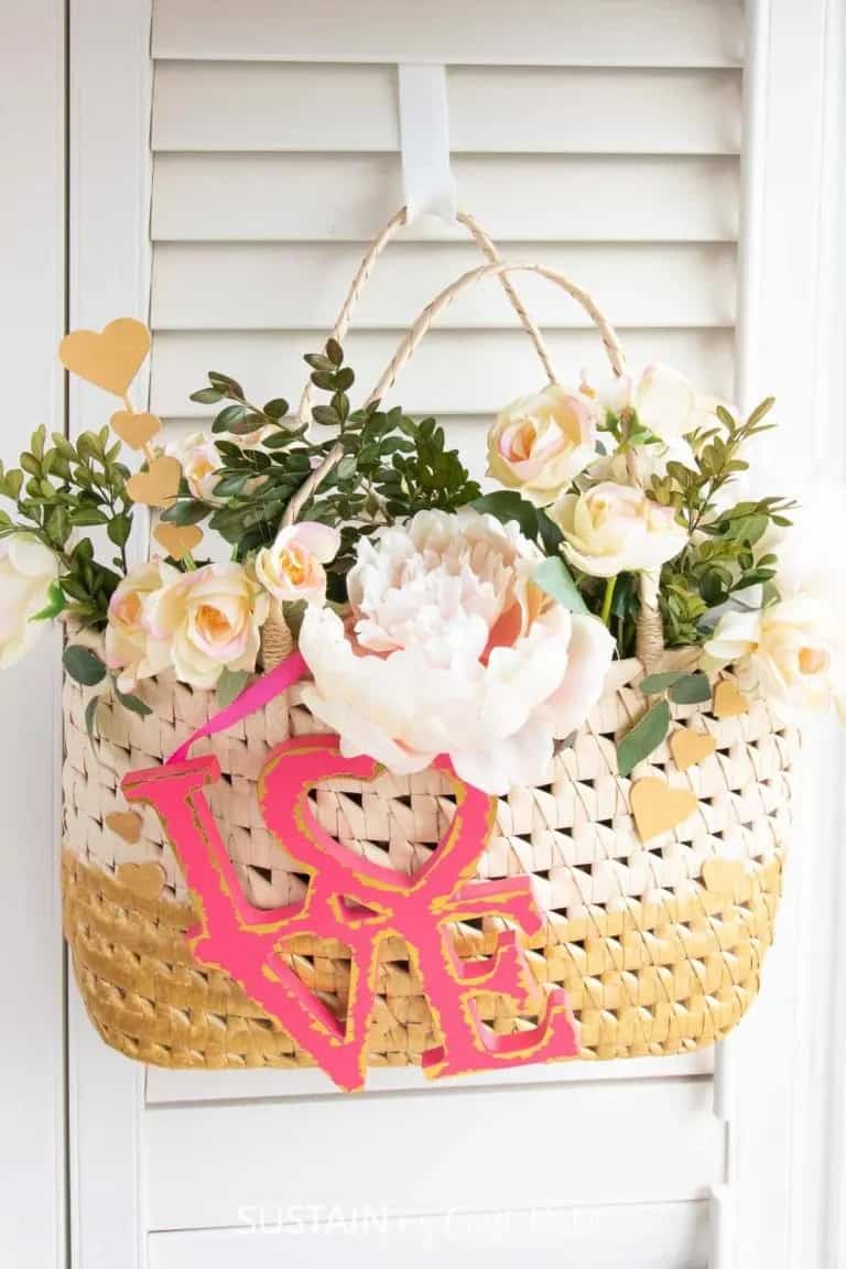 Decorated straw bag with flowers and a love sign hanging on blinds